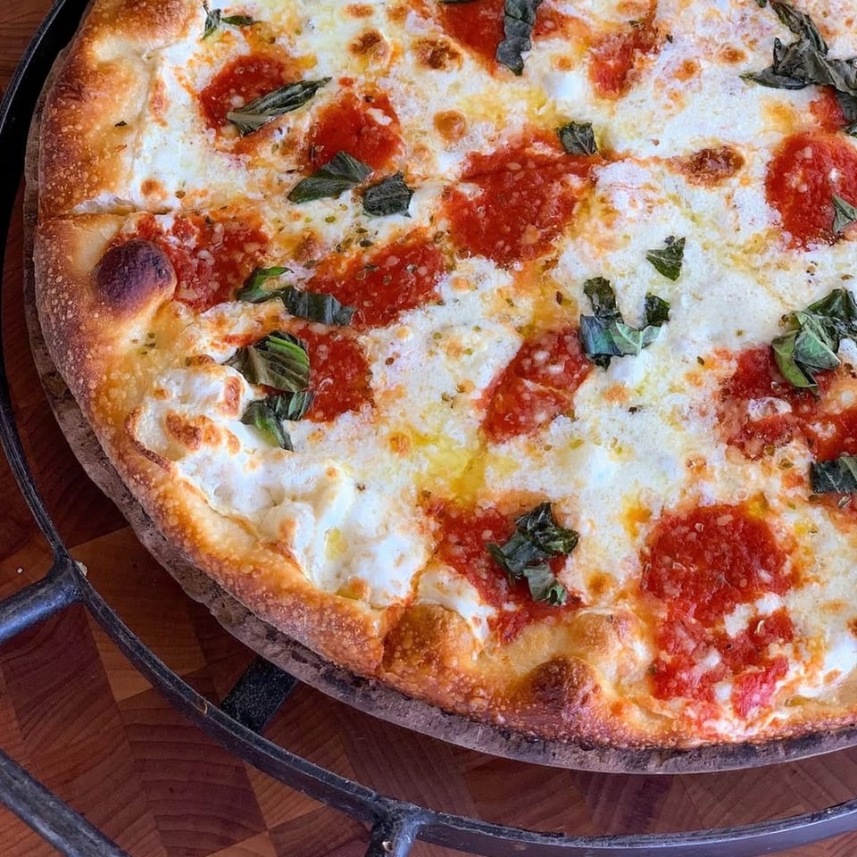 A close-up of a freshly baked pizza with melted mozzarella, red sauce, and basil leaves.